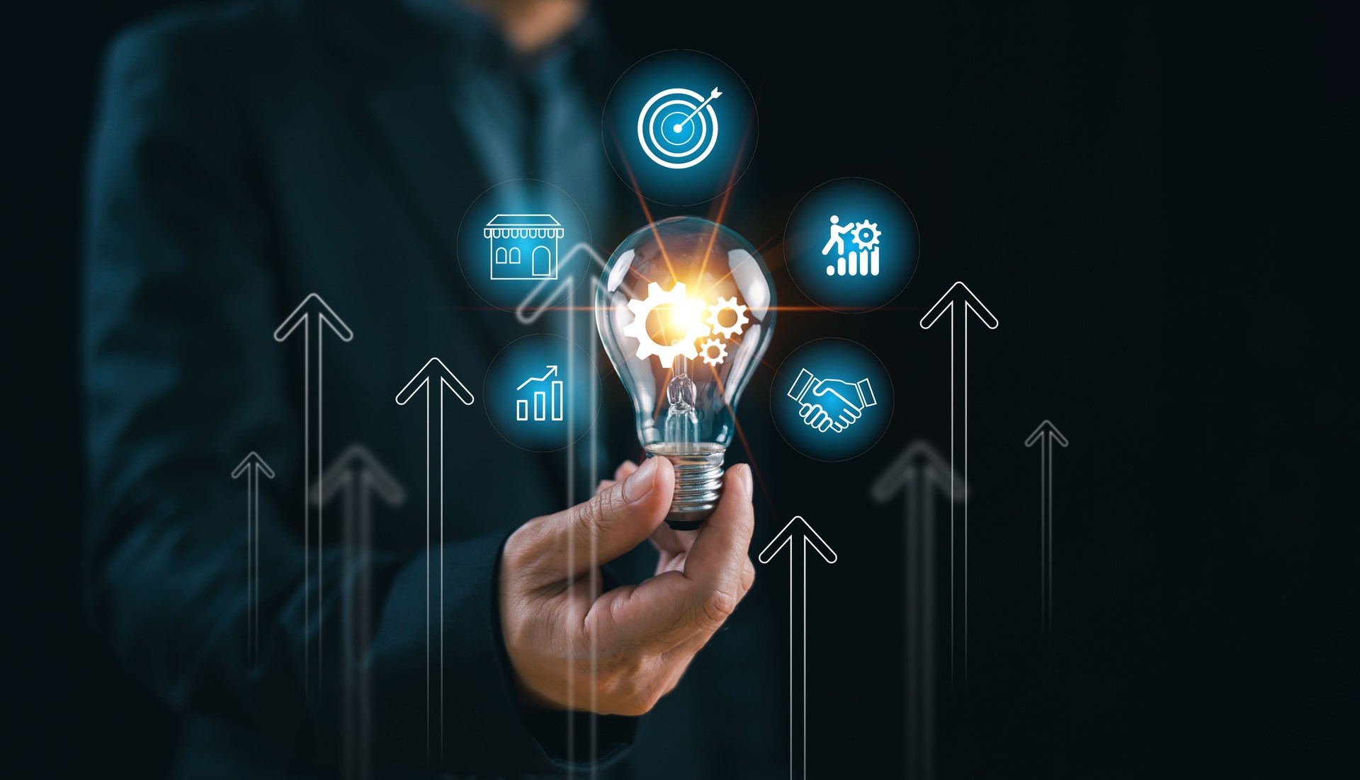 Hand holding Lightbulb with icons about business surrounding it